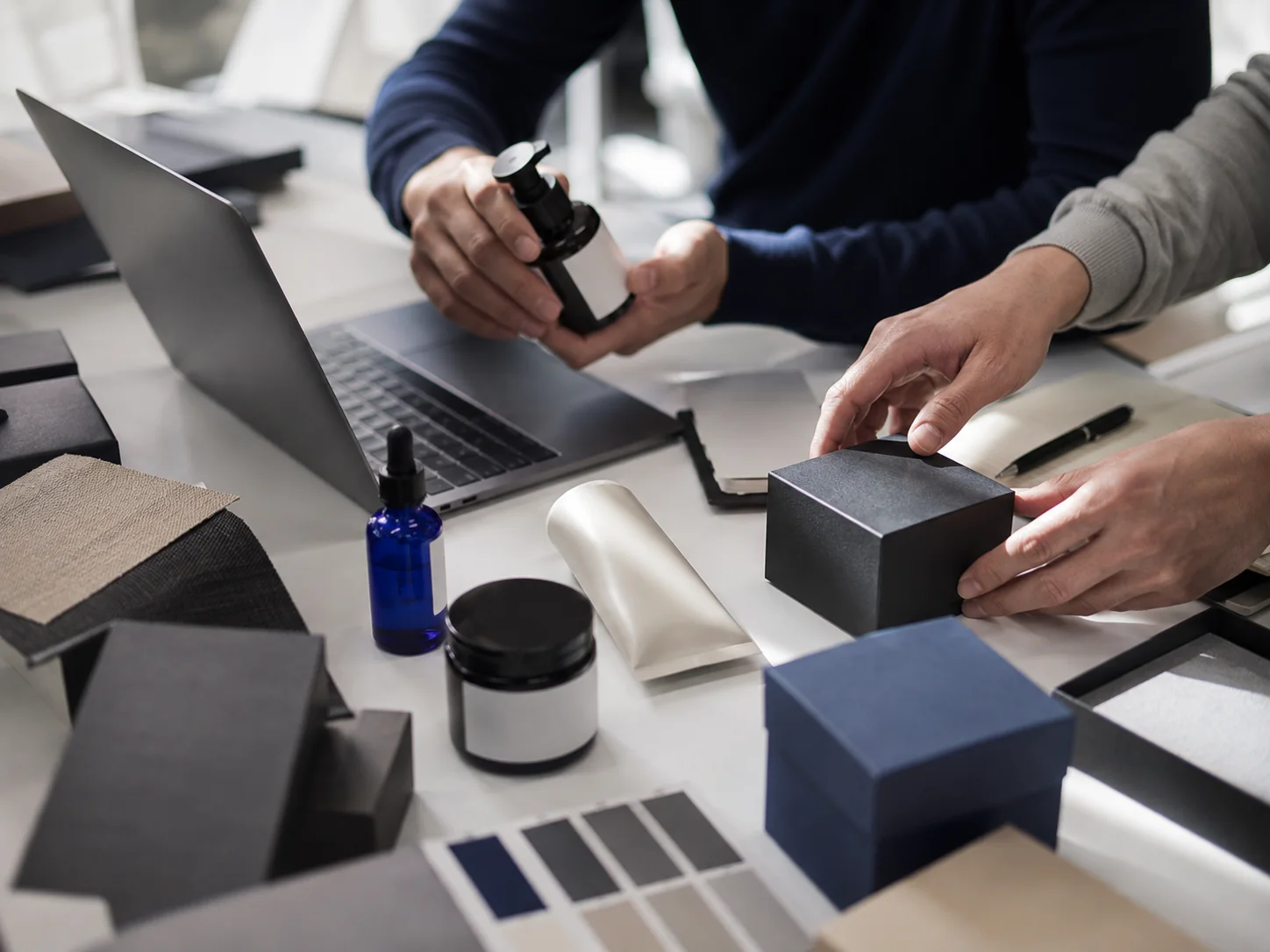 Hands arranging unbranded retail products during a commerce planning session
